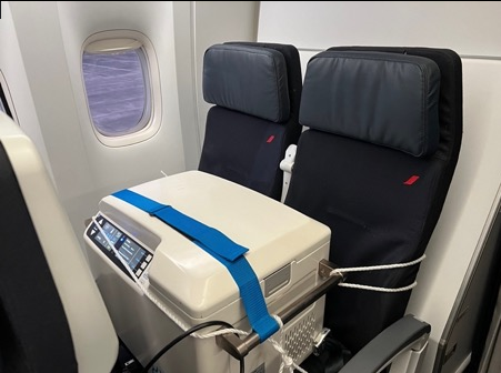 Heart being transported across the atlantic for organ donation. heart transplant transport box taking up 2 passenger seats